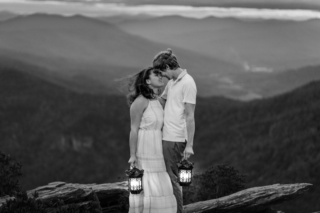 Romantic mountain engagement photo taken at blue hour with lantern light, overlooking the Blue Ridge Parkway.