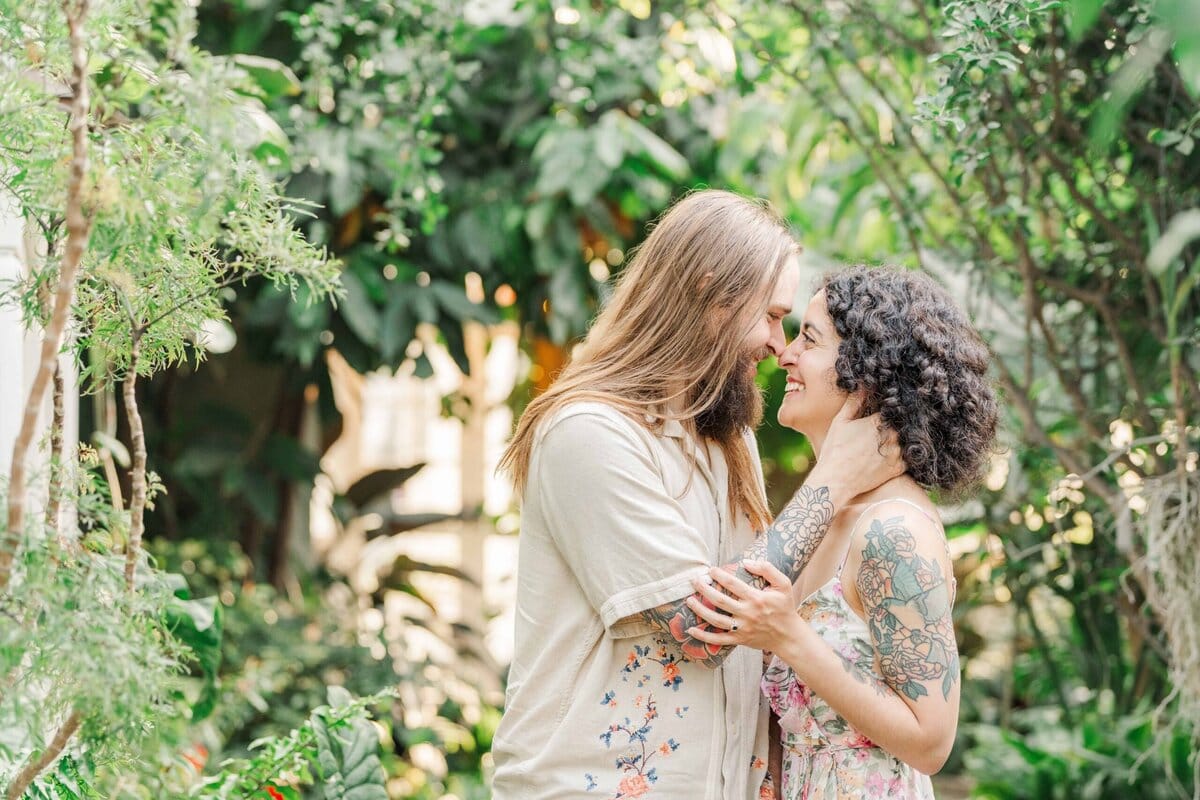 Couple smiling in front of tropical greenery inside the Orchid Conservatory