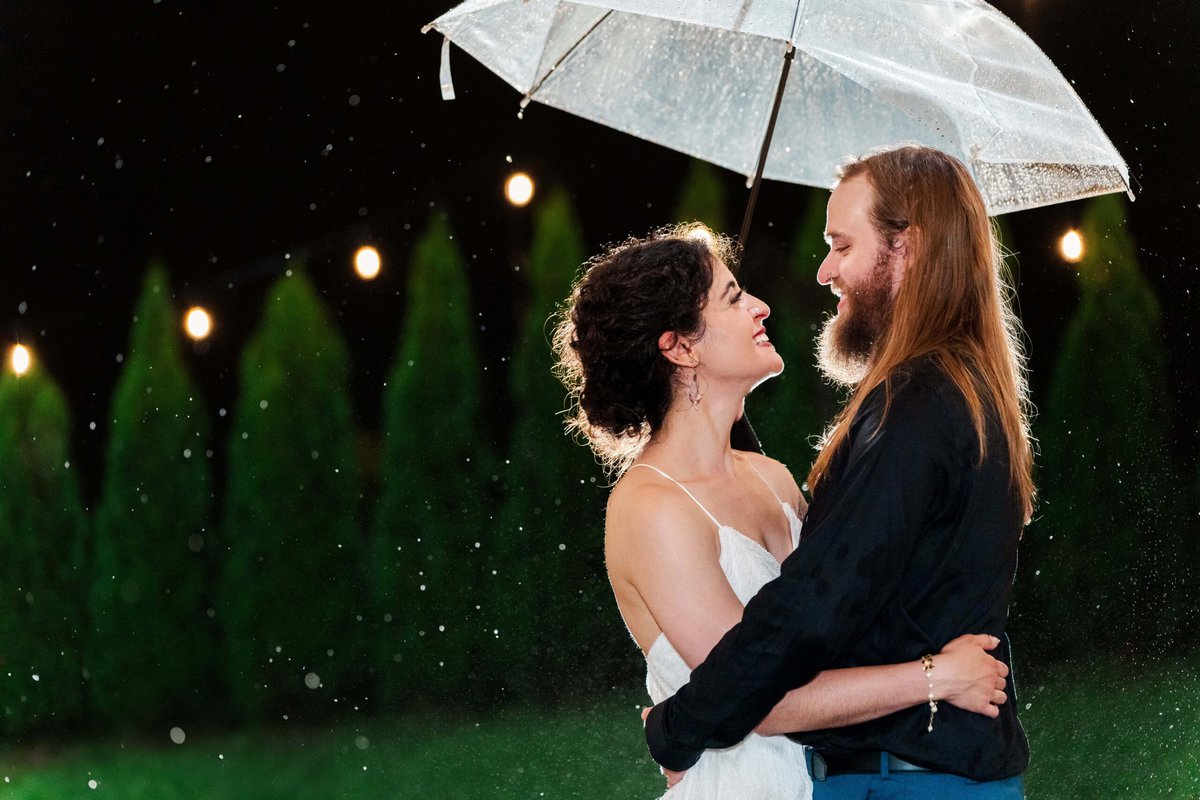 Romantic rainy night photo under string lights at Mariposa Chapel wedding