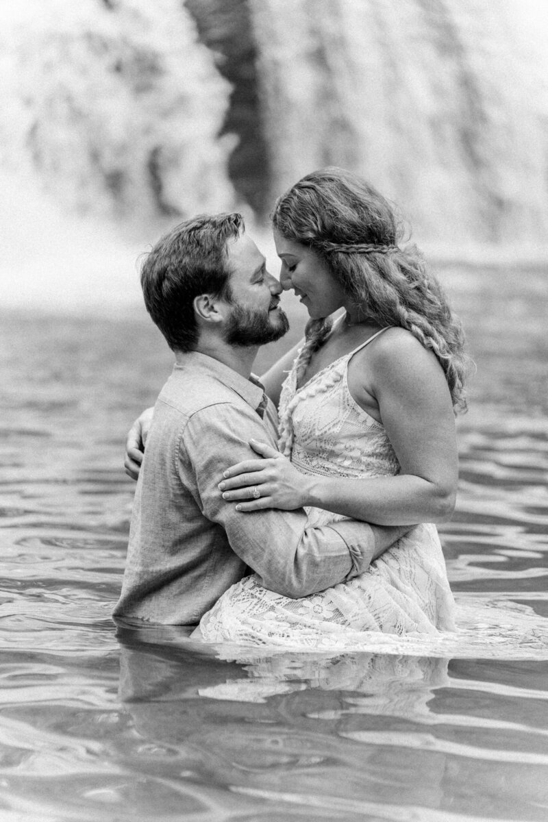 Alex and Brad kissing under McGalliard Falls during their outdoor engagement session