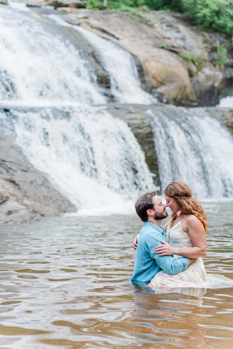 Romantic photo of couple under waterfall at McGalliard Falls engagement session