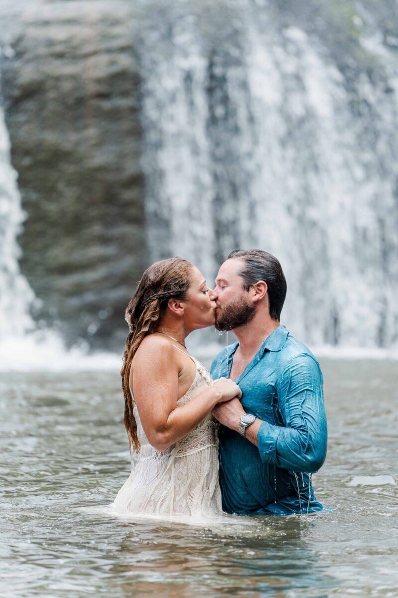 Couple kissing under the waterfall at McGalliard Falls engagement session