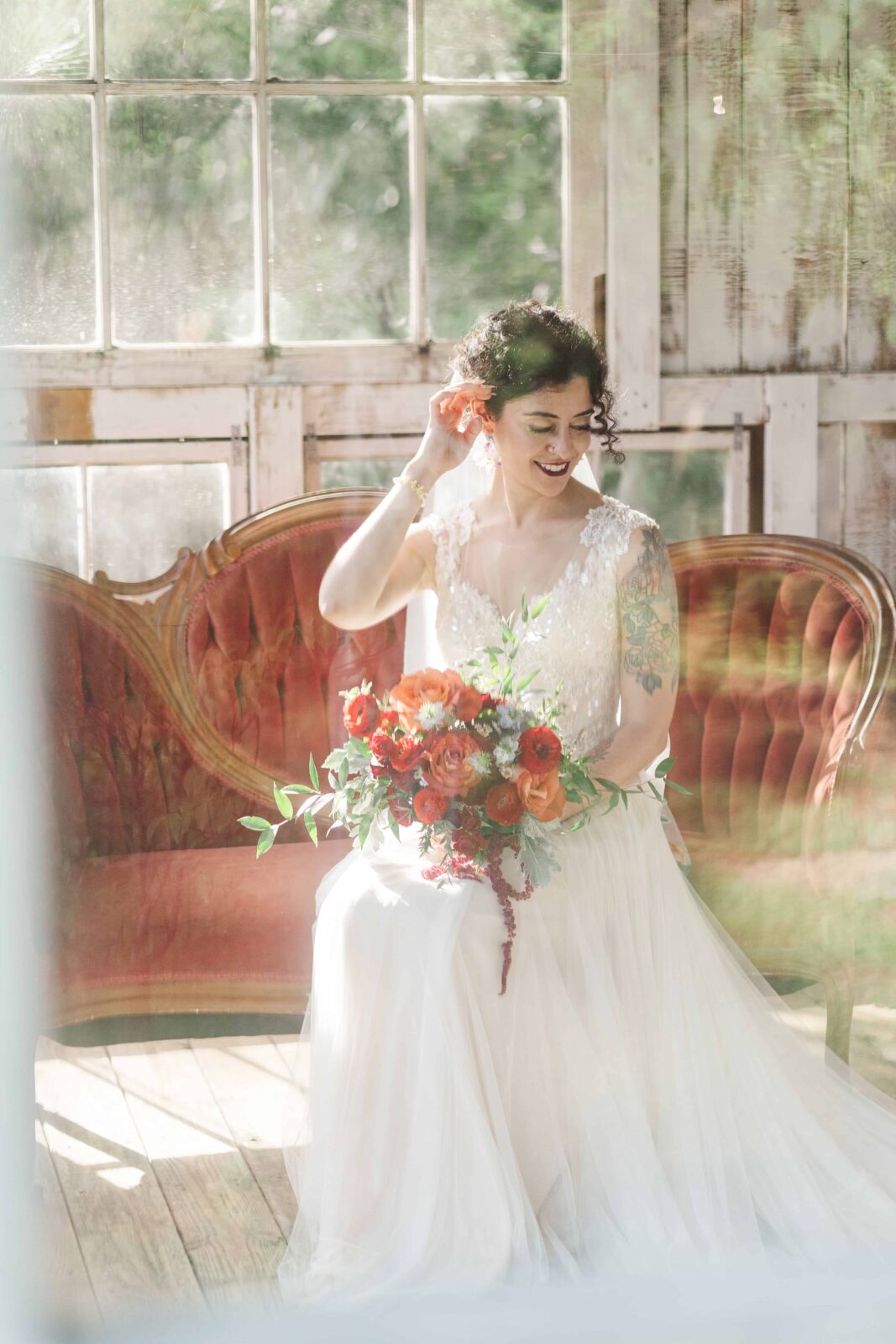 Creative portrait of bride taken through the greenhouse window. Make sure to prioritize photography in your wedding budget to capture images like this