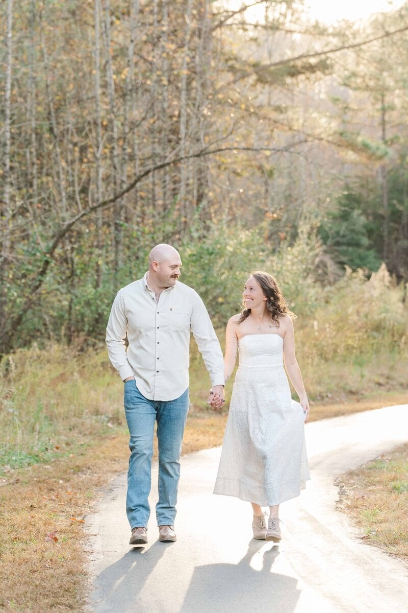 Playful engagement pose with couple laughing in natural setting