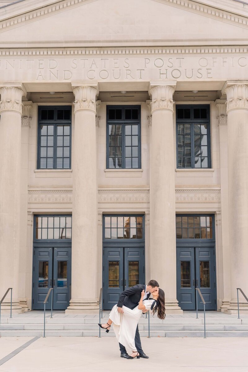 Uptown Charlotte engagement photos of couple standing by white columns at courthouse