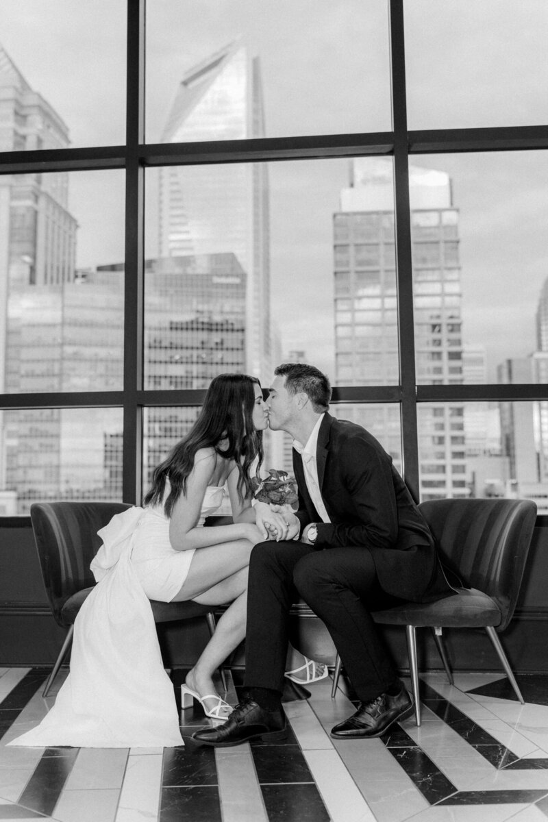 Couple holding hands with Charlotte skyline visible through large windows