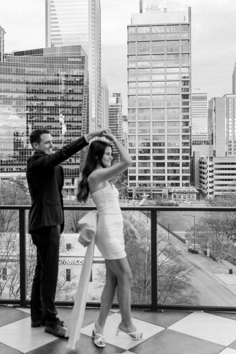 City skyline engagement photo taken from rooftop lounge in Charlotte