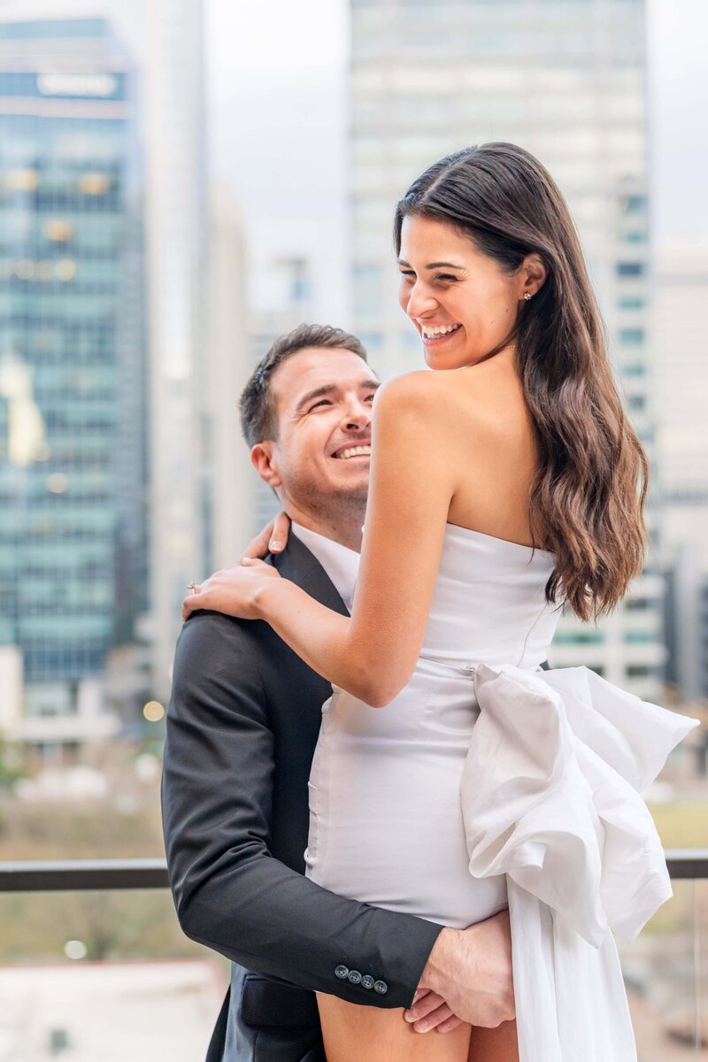 Skyline filled engagement photo showing couple embracing in Charlotte area