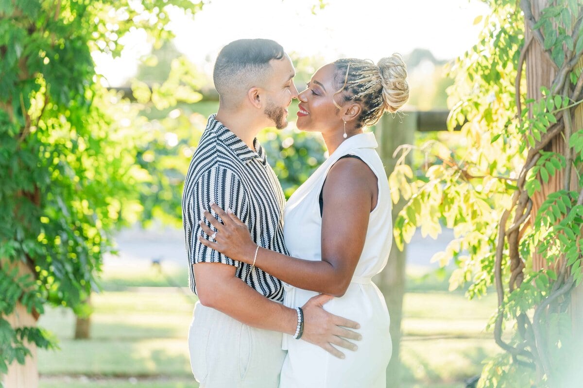 Gelisa and Juan embracing in the vineyard at Spinning Leaf at Wedgewood Weddings in Shelby NC during their engagement session with golden sunset light.