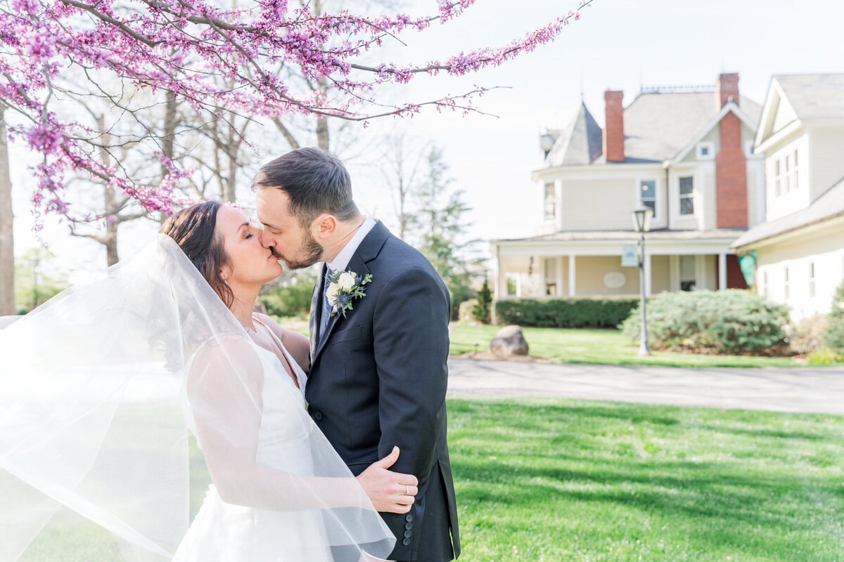 Bride and groom portraits underneath blooming redbud tree at Alexander Homestead spring wedding