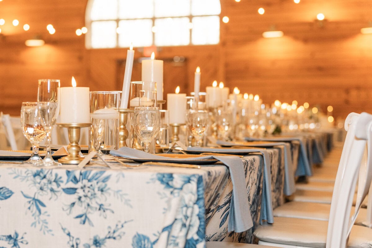 Close up of white floral table linens with candles and blue hydrangeas at Alexander Homestead wedding reception
