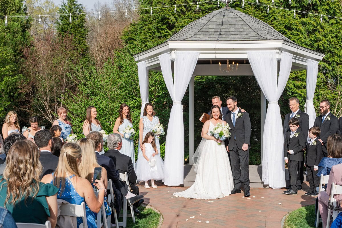 Couple holding hands during intimate ceremony in the gardens at historic Alexander Homestead