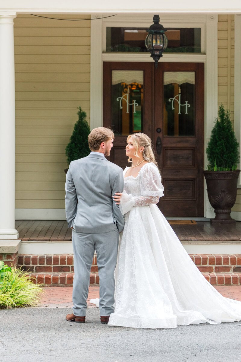 Bride in long sleeve lace gown with full train on the staircase inside the historic Alexander Homestead manor, Charlotte NC wedding photographer