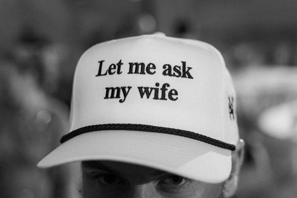 Groom Alex wearing hat that reads Let me ask my wife during reception at Alexander Homestead by Wedgewood Weddings