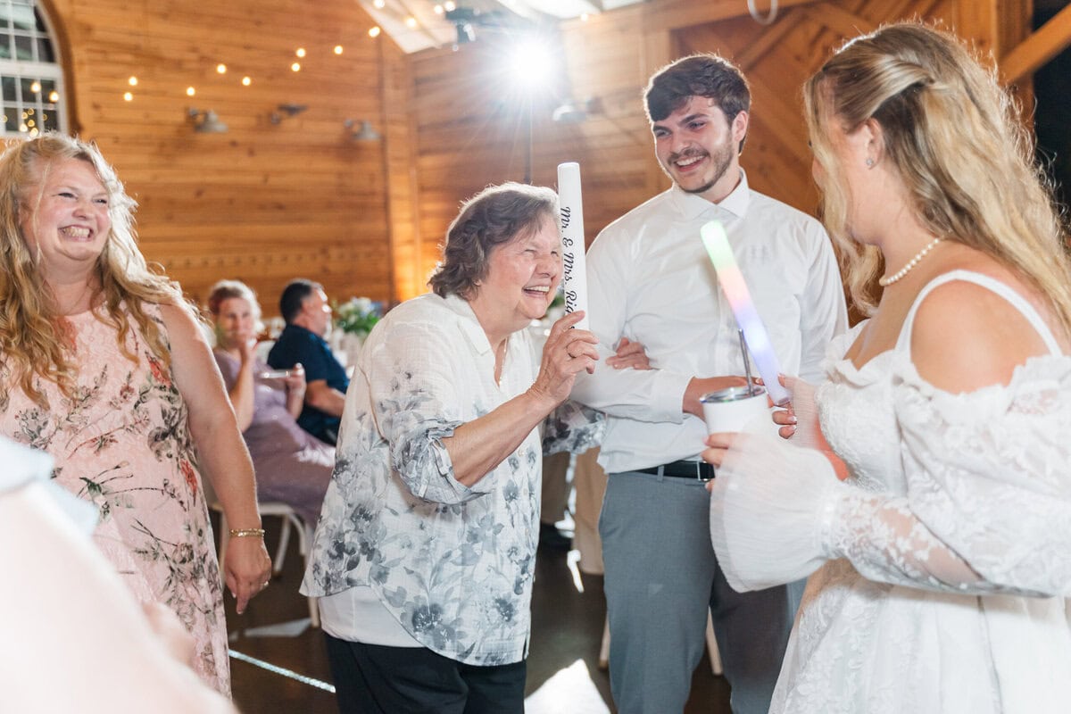Wedding guests dancing under bistro lights in the reception barn at historic Alexander Homestead, Charlotte NC