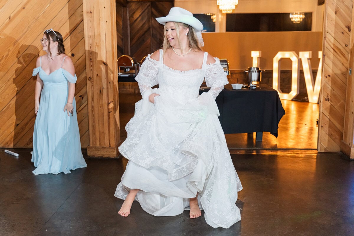 Bride Samantha dancing in lace wedding gown with full train at Alexander Homestead reception barn, Charlotte NC