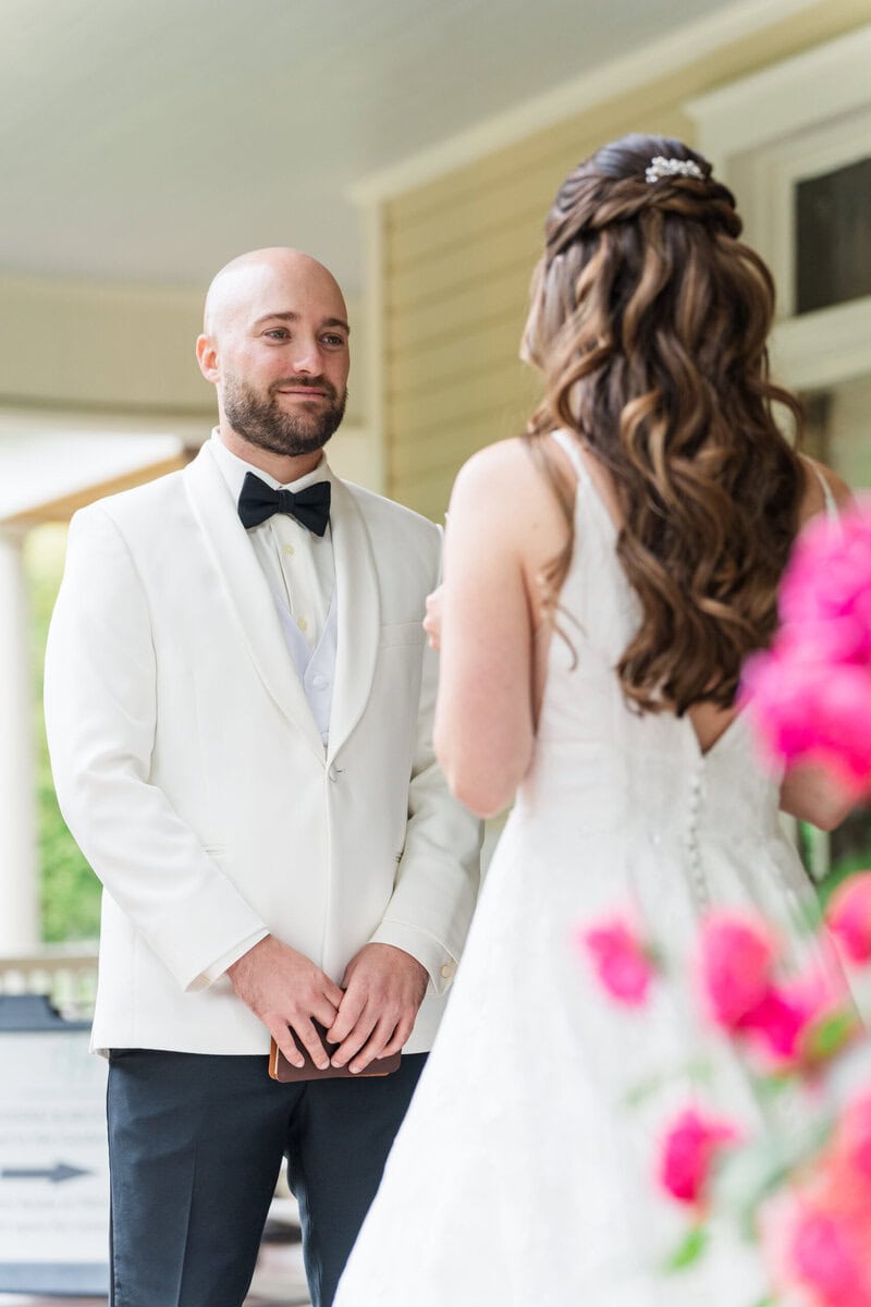 Groom in white suit coat and black bow tie standing in the garden at Alexander Homestead Charlotte NC