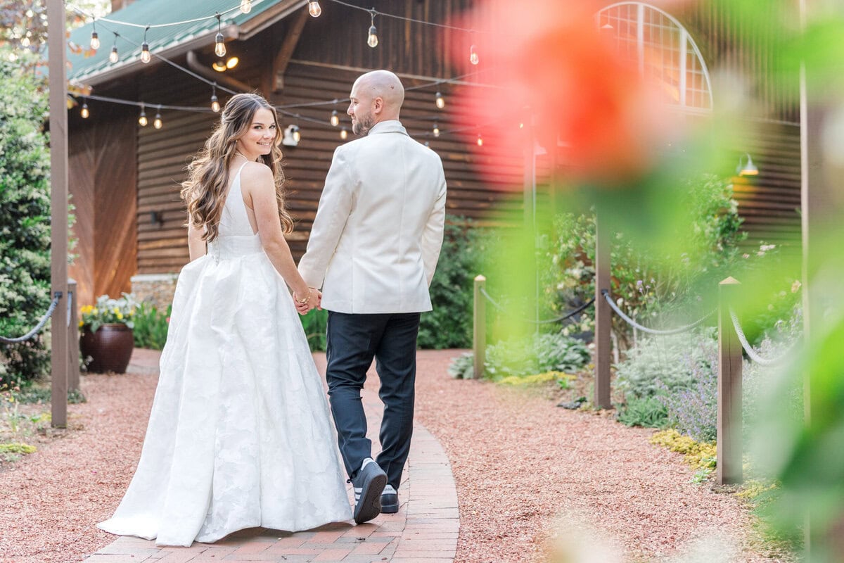 Bride and groom walking through rose garden at Alexander Homestead spring wedding Charlotte NC