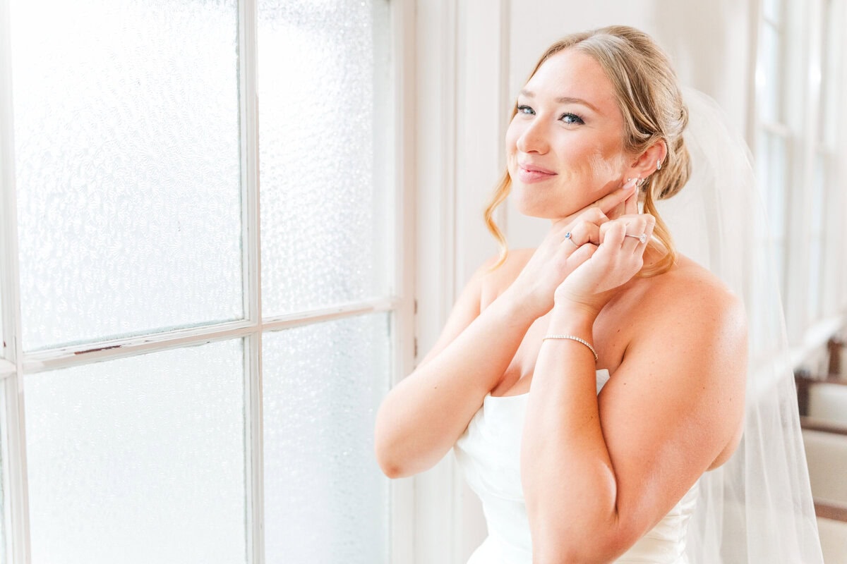 bride in wedding dress standing in front of white chapel windows soft spring light Iron Station NC