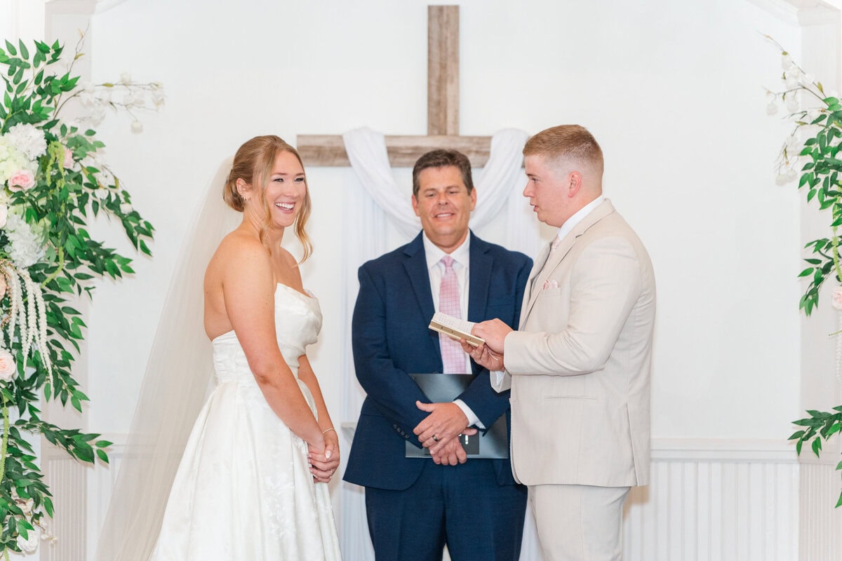bride and groom exchanging vows inside little white chapel Mariposa Chapel Iron Station NC