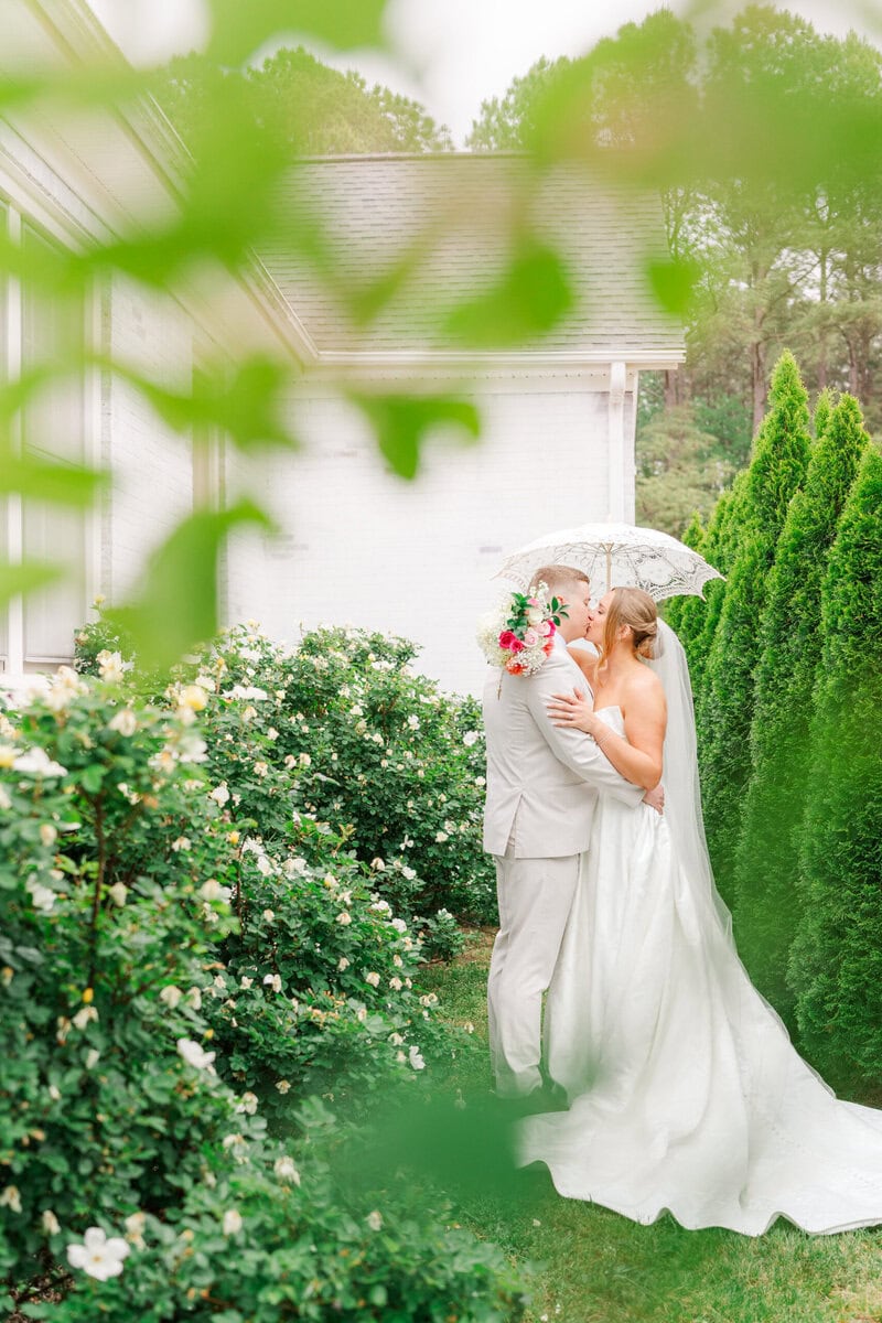 bride and groom kissing in the rain at historic white chapel wedding near Charlotte NC