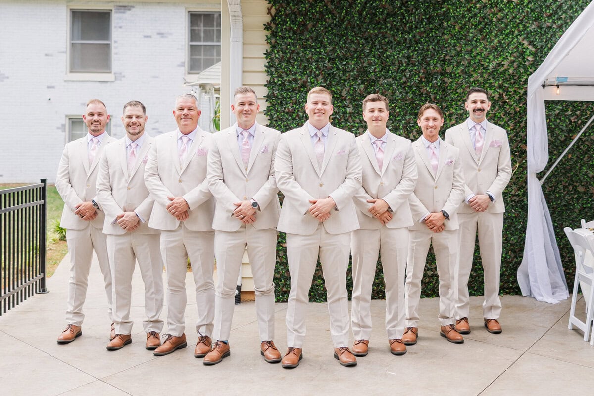 groom and groomsmen in tan suits pink ties at Mariposa Chapel little white chapel wedding near Charlotte