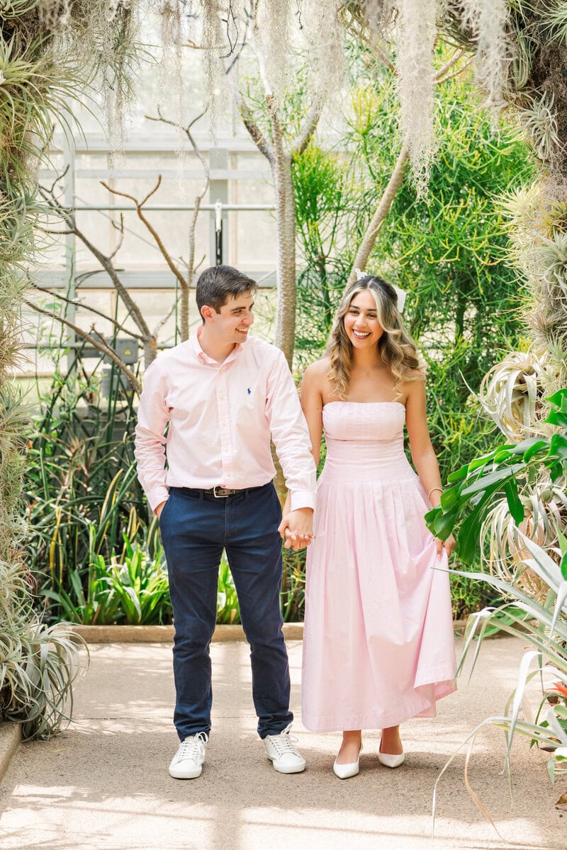 Newly engaged couple laughing together during portrait session inside Daniel Stowe Botanical Garden Orchid Conservatory Charlotte area proposal photographer The Lilac Lion Photography