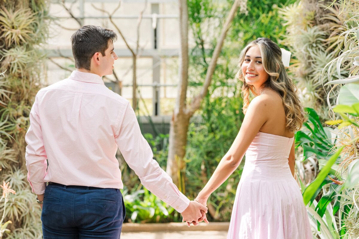 Engaged couple walking together through Daniel Stowe Botanical Garden in Belmont NC during spring proposal photography session with The Lilac Lion Photography