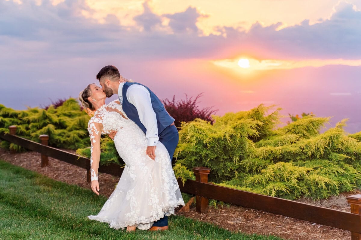 Bride and groom portraits at sunset at Hidden Hill Venue with pink and orange sky over Blue Ridge Mountains