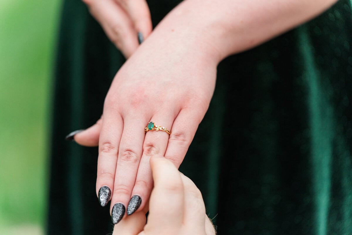 Bride-to-be with emerald ring laughing at rainy engagement session at Providence Cotton Mill