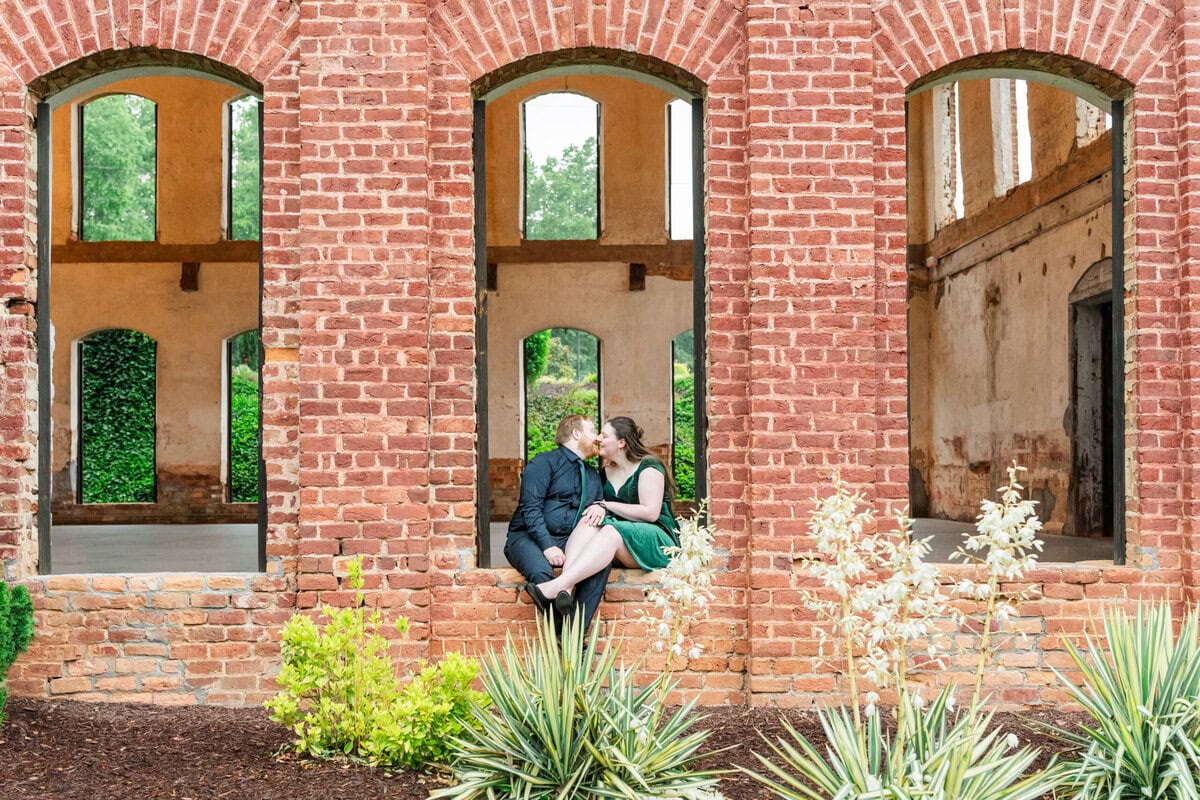 Couple posing near arched windows inside The Providence Cotton Mill during engagement photos