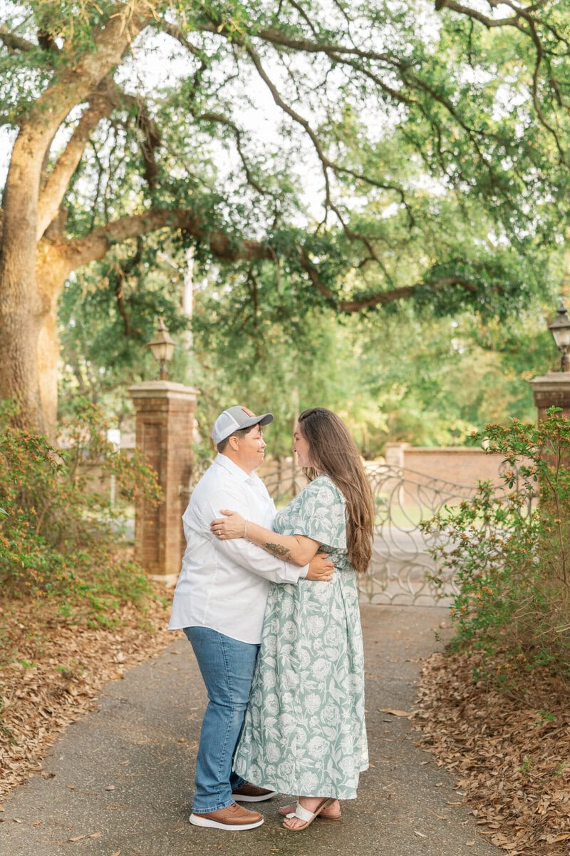 Nikki and Ashley posed under mature trees with dappled natural light at Kamila Gardens