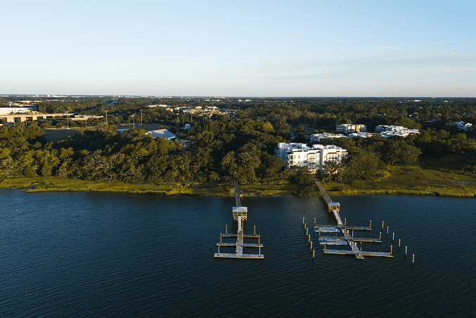 Aerial view of The Marshes in Delaware showcasing scenic waterfront living with boat docks, lush greenery, and modern residential buildings, perfect for outdoor recreation and relaxing by the water.