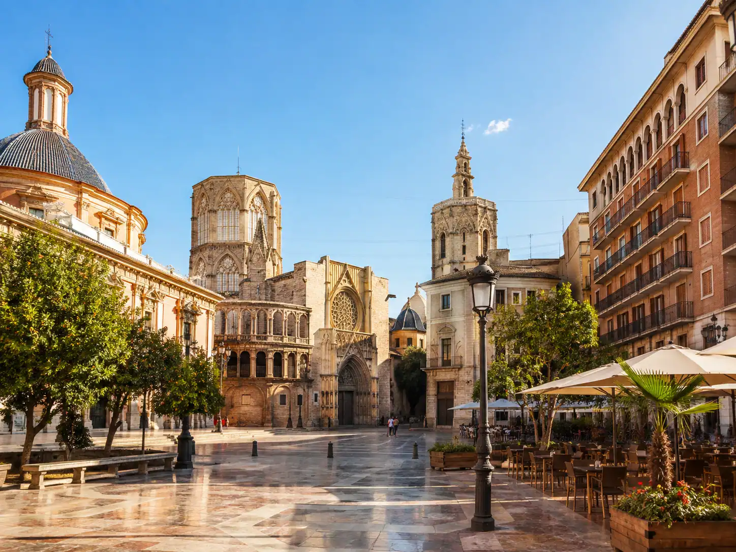 Sunlit historic square in Valencia old town with Mediterranean architecture and outdoor cafés