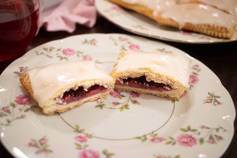 a sourdough pop tart filled with fruit jam cut into two on a pink floral china plate