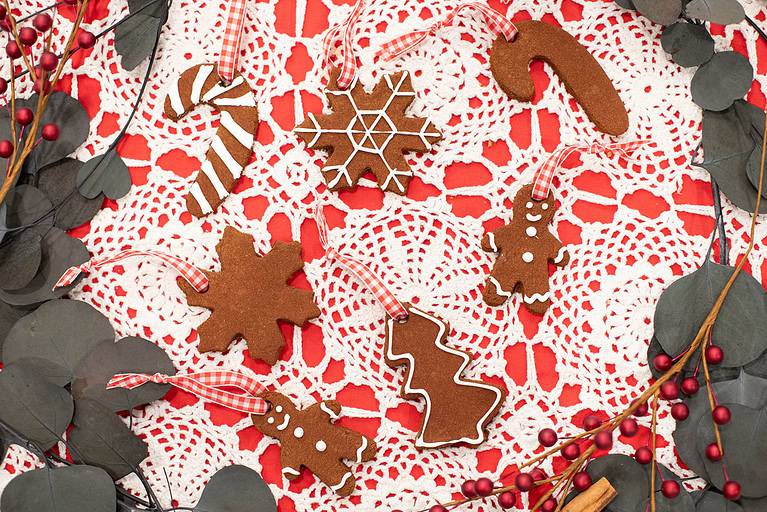 Cinnamon applesauce ornaments in festive shapes like gingerbread people and stars, displayed on a red and white holiday tablecloth.