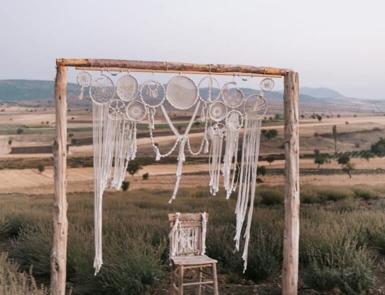Bohemian style wedding arbor and wooden chair set against the rustic landscape.