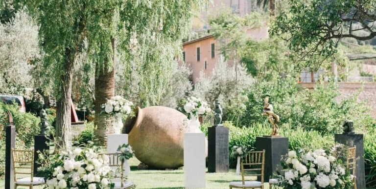 Elegant outdoor garden wedding scene with floral arrangements and mountain backdrop.