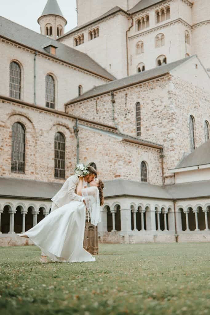 A couple embraces in front of the historic Nivelles Cathedral in Belgium, symbolizing love and tradition.