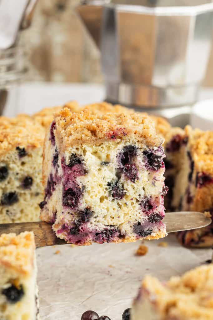 serving a slice of huckleberry coffee cake on a spatula.
