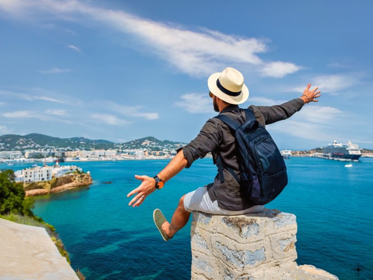 Man sitting on pier infront a blue ocean with his arms extended