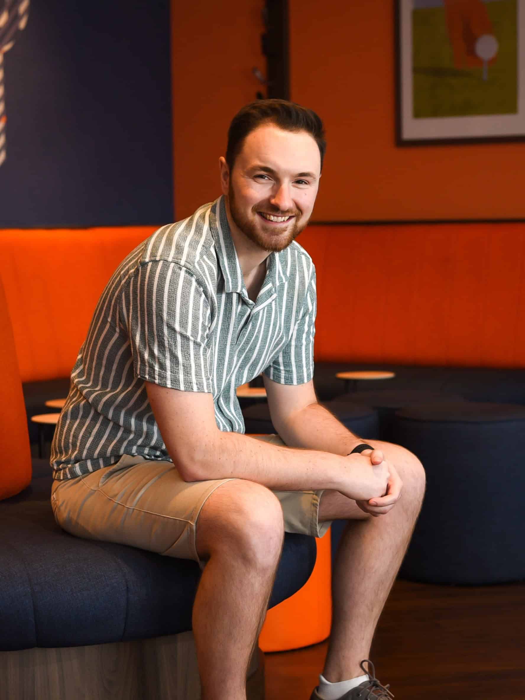 Relaxed young man enjoying casual indoor setting, modern decor, leisure, smiling, The Wandering Woodward.