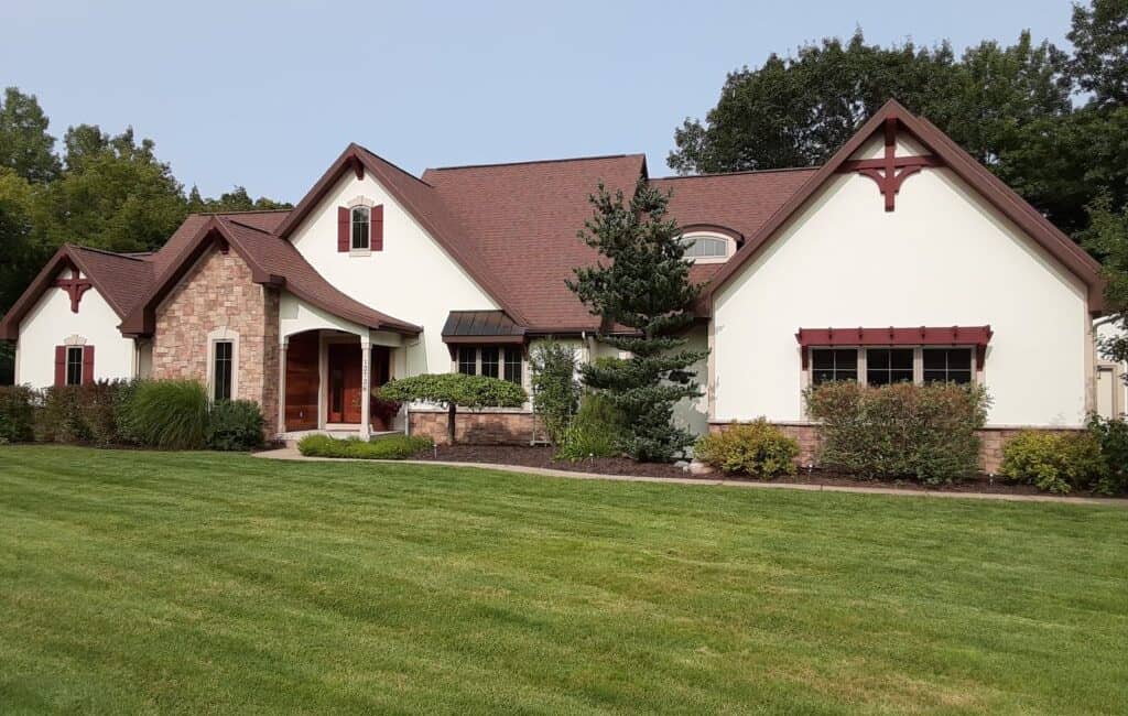 Elegant house with a combination of brick and white stucco exterior, gabled roof, and lush landscaping, showcasing expert residential painting and exterior painting services.