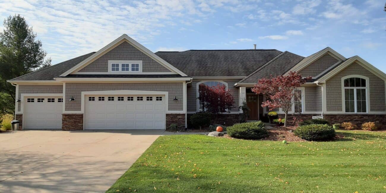 Vibrant house exterior painted with a neutral color palette, featuring a manicured lawn, decorative trees, and updated windows, showcasing professional residential painting services from Thornapple Painting.