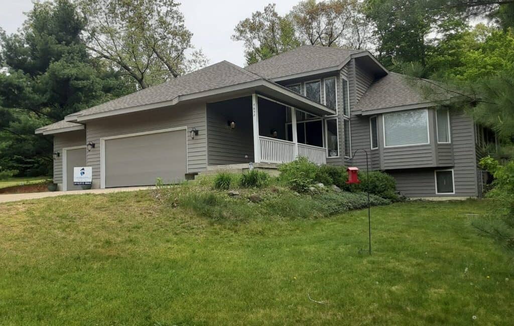 Modern gray house with a screened porch and well-maintained lawn, showcasing professional exterior painting services by Thornapple Painting.