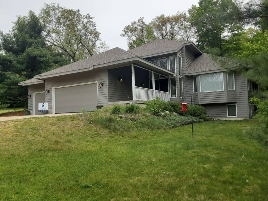 Modern gray house with a screened porch and well-maintained lawn, showcasing professional exterior painting services by Thornapple Painting.