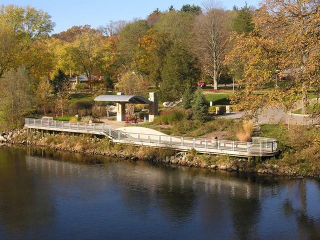 Riverside park with walking path, ramp, gazebo, and colorful autumn trees along the Thornapple River in Michigan.