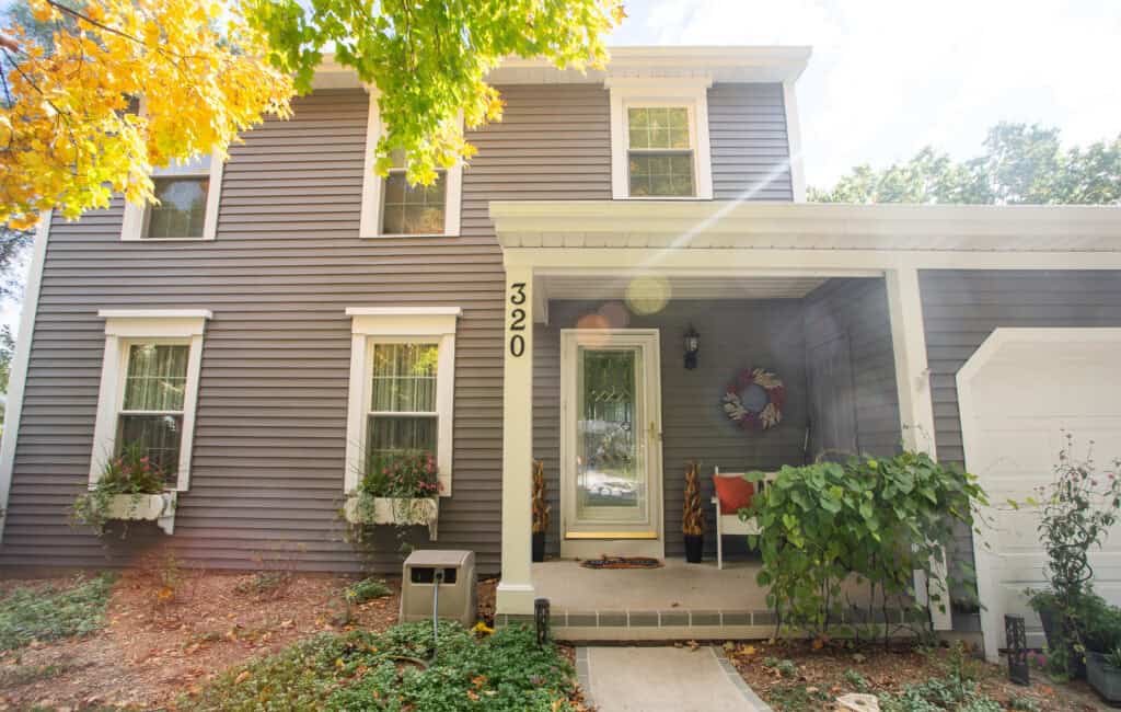Bright gray house exterior with fresh paint,white trim, and decorative wreath, showcasing professional residential painting services by Thornapple Painting.