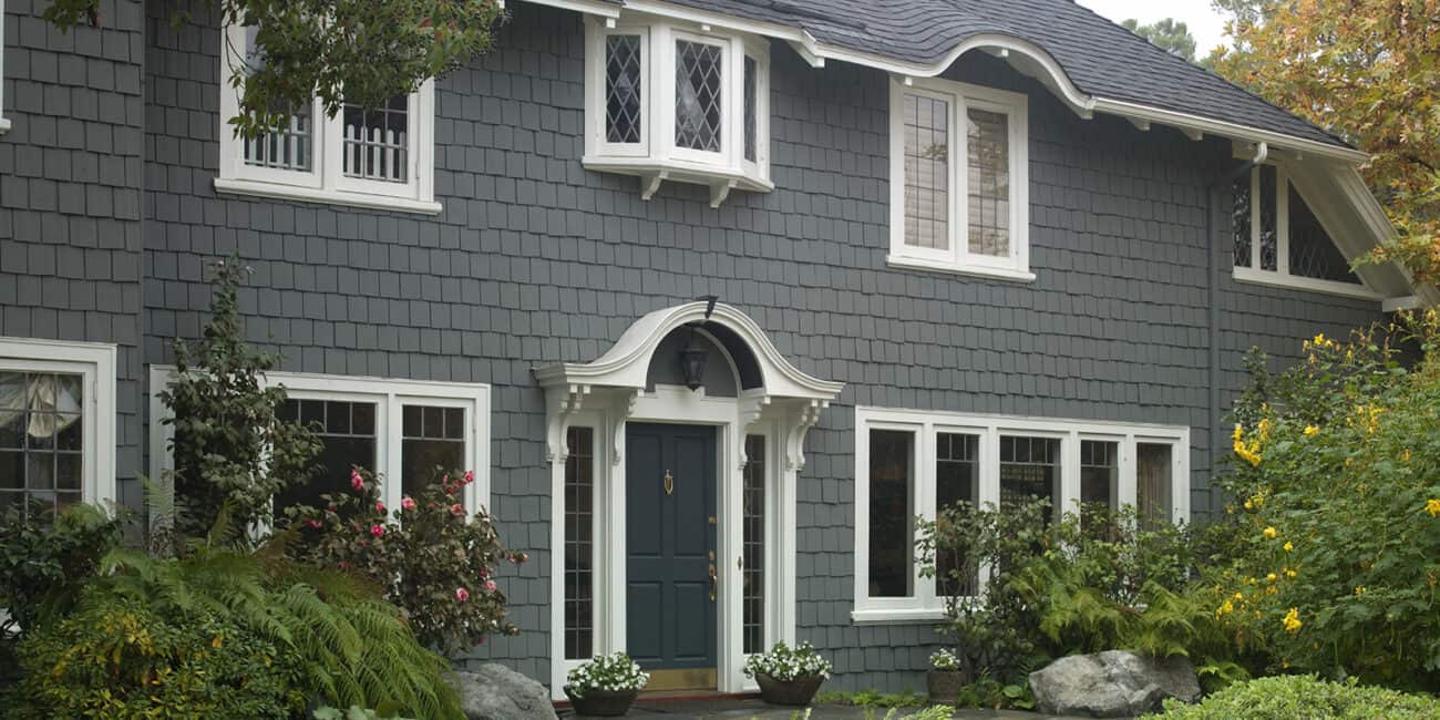 Bright blue painted house exterior with classic white trim and decorative architectural details, showcasing expert residential painting and weatherproofing services.