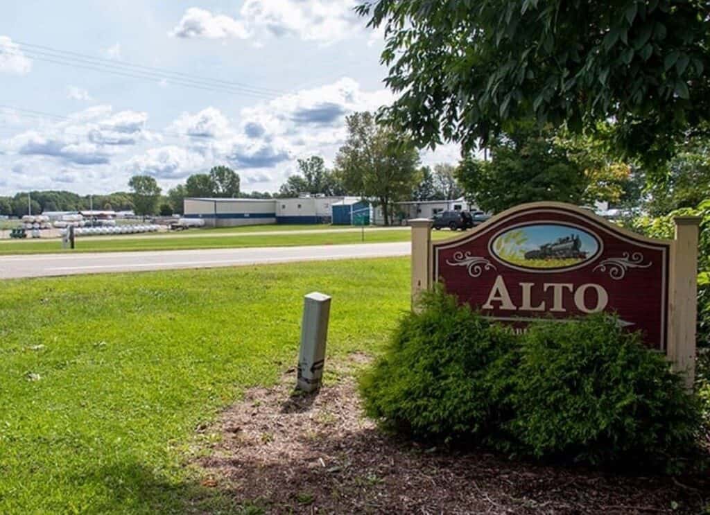 Alto sign with lush greenery and industrial buildings in the background, showcasing a well-maintained landscape, perfect for highlighting local scenery in painting or home improvement projects.